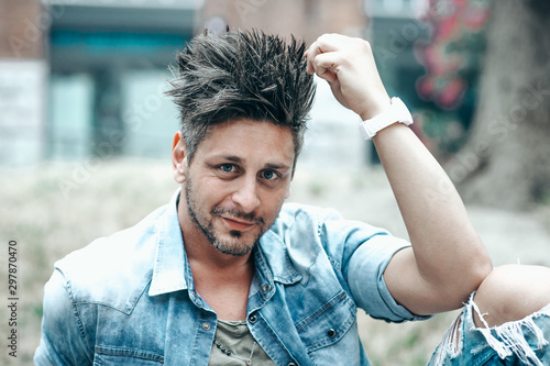 Portrait of handsome man in casual clothing posing in the pubblic garden , looking away to a side. Color Toned Image. Concept urban man. photo