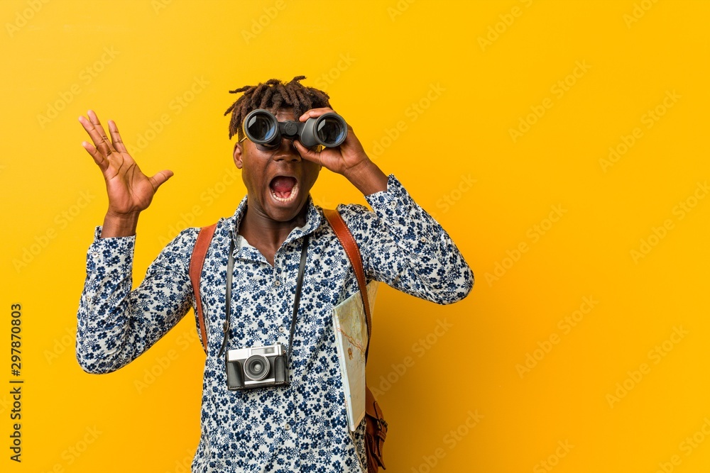 Young african tourist man standing against a yellow background holding a binoculars Young african tourist man standing against a yellow background holding a binoculars