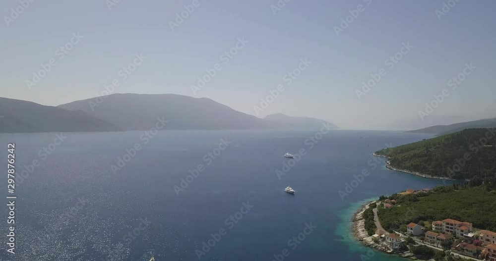 Drone shot of distant mountains passing over a greek village in the summer sun Drone shot of distant mountains passing over a greek village in the summer sun