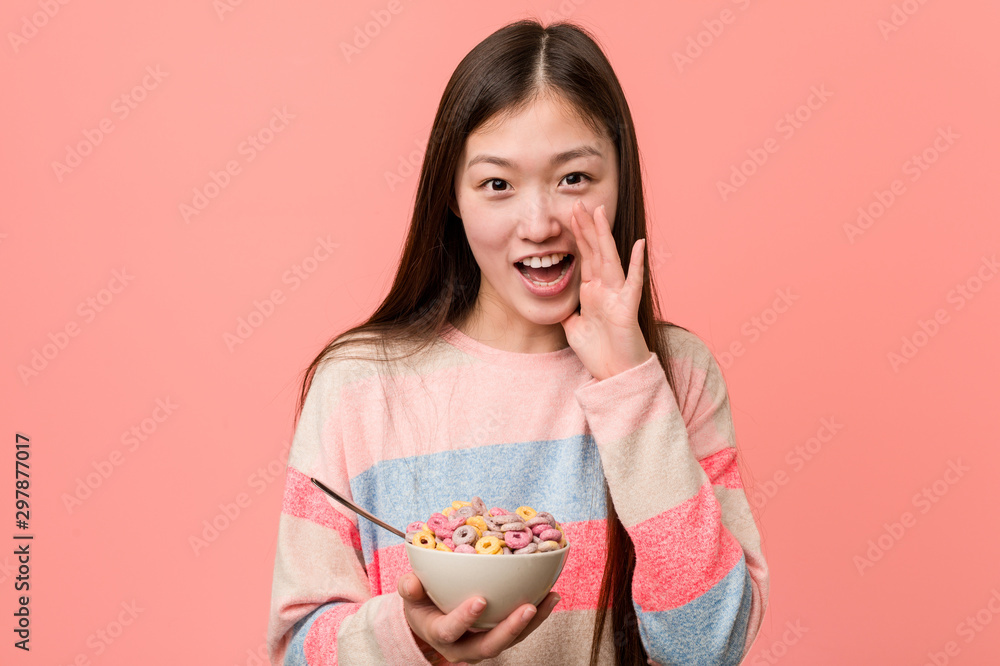 Young asian woman with a cereal bowl shouting excited to front. Young asian woman with a cereal bowl shouting excited to front.