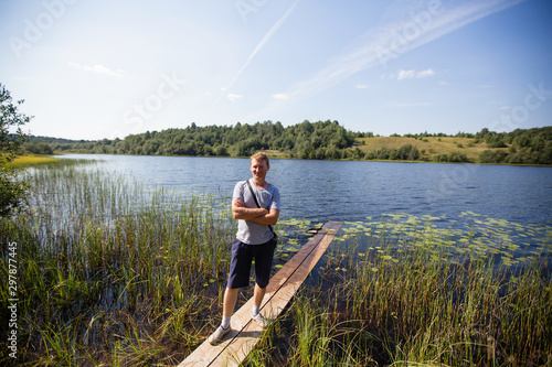 Young man on the river with a wooden boards in the summer in the village.