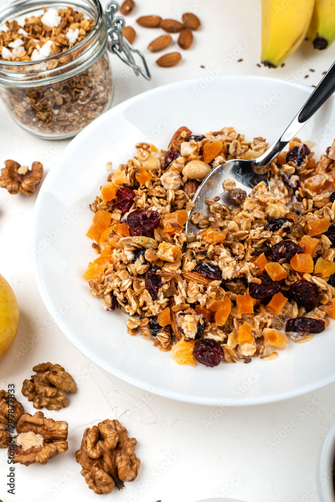 Granola muesli breakfast with with milk, dried apricots, cranberries, almonds and flax seeds in bowl on a white background. Healthy cereal breakfast. Granola muesli breakfast with with milk, dried apricots, cranberries, almonds and flax seeds in bowl on a white background. Healthy cereal breakfast.
