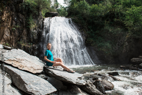 Woman at Korbu Waterfall on the Lake Teletskoye in autumn Altai Mountains.