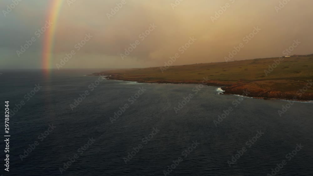 Aerial, rugged coastline with distinct colorful rainbow and rain cloud Aerial, rugged coastline with distinct colorful rainbow and rain cloud