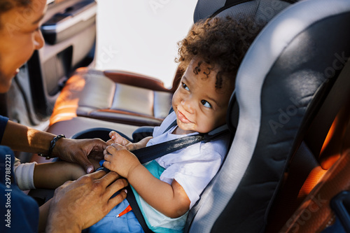 Smiling baby boy looking at his mother while sitting fastened in a car seat