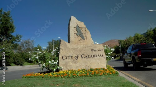 Handheld shot of a huge graven rock, Welcome City of Calabasas sign while a pickup driving by. Home of the Kardashians, photo