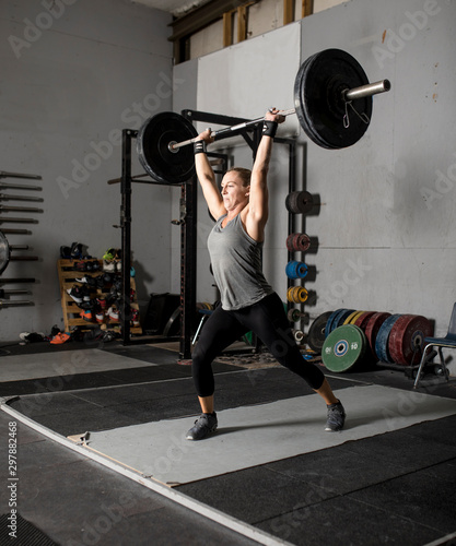 Strong femal weight lifter with heavy weights over her head, two thirds profile shot.