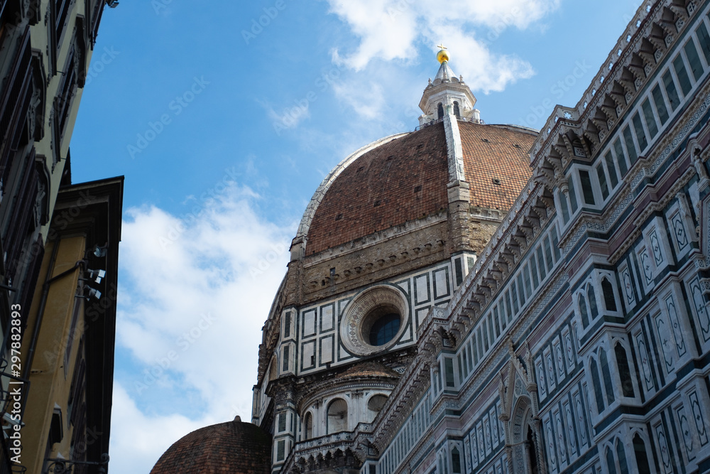 Obraz premium Florence's Santa Maria del Fiore Dome seen from the side with clouds and blue sky.