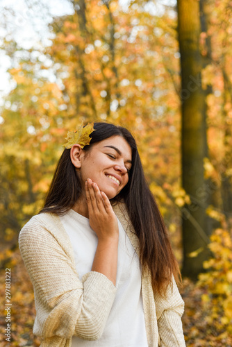 Beautiful brunette in white sweater strolls in the autumn park