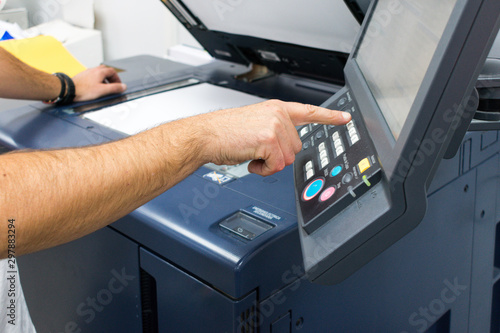 Caucasian adult male hand on the control panel of a photocopier