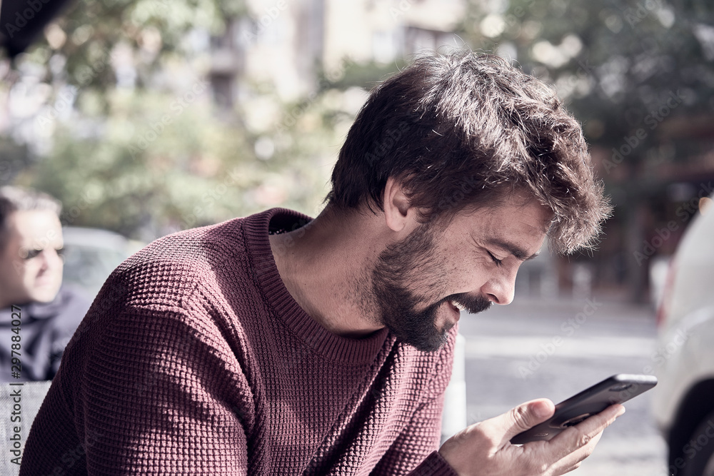 Fototapeta premium Attractive young bearded man using his smartphone in the cafe