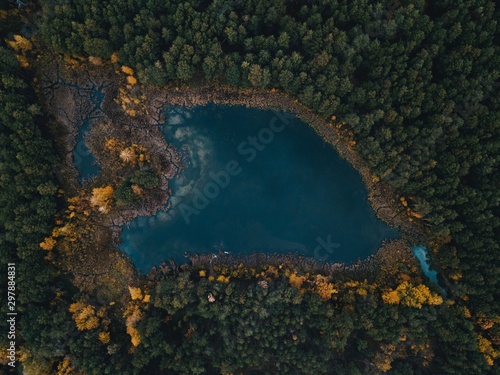 Aerial shot of lake surrounded by forest autumn trees