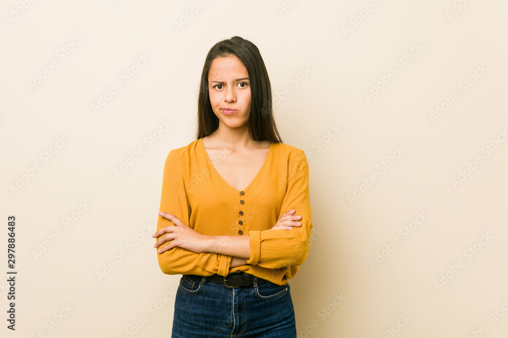 Young hispanic woman against a beige background unhappy looking in camera with sarcastic expression. Young hispanic woman against a beige background unhappy looking in camera with sarcastic expression.