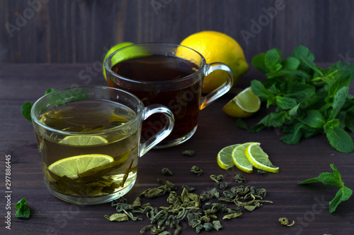 healthy lifestyle. cups of green and black tea with lemon and leaves of green mint on wooden background. cups of green and black tea with lemon and leaves of green mint on wooden background. 