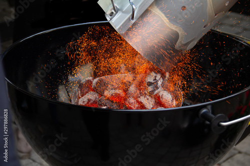 Adding glowing charcoal to the grill