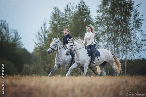 Two women enjoy riding horses outdoors.  © Osetrik
