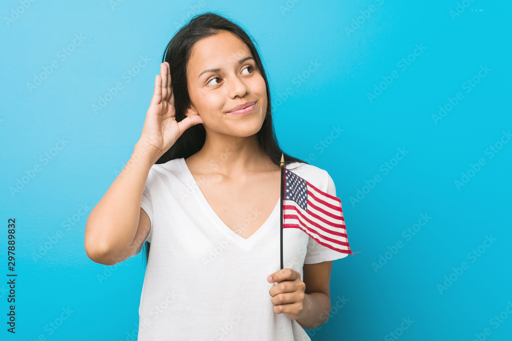 Young hispanic woman holding a united states flag trying to listening a gossip. Young hispanic woman holding a united states flag trying to listening a gossip.