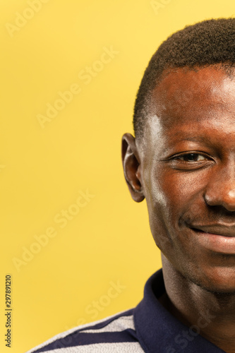 African-american young man's close up portrait on yellow studio background. Beautiful male model with well-kept skin. Concept of human emotions, facial expression, sales, ad. Looks happy and calm.