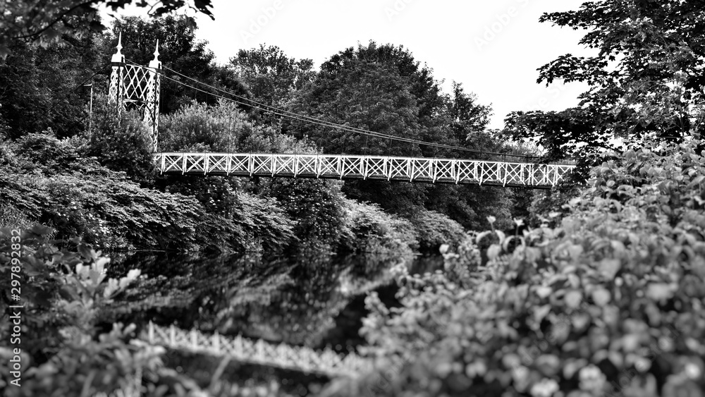 Obraz premium Howley suspension footbridge at victoria park passing over the river mersey. This bridge is around 100 years old and is hidden gem in warrington town, first ever taken this way. England 