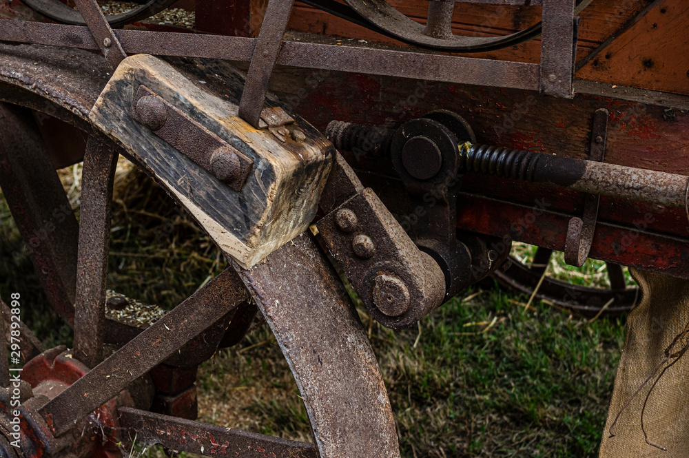 Bremse eines historischen landwirtschaftlichen Fahrzeugs, einer Dreschmaschine, bestehend aus  Bremsklotz aus Holz, Rad aus Stahl und Betätigungsgestänge aus Stahl