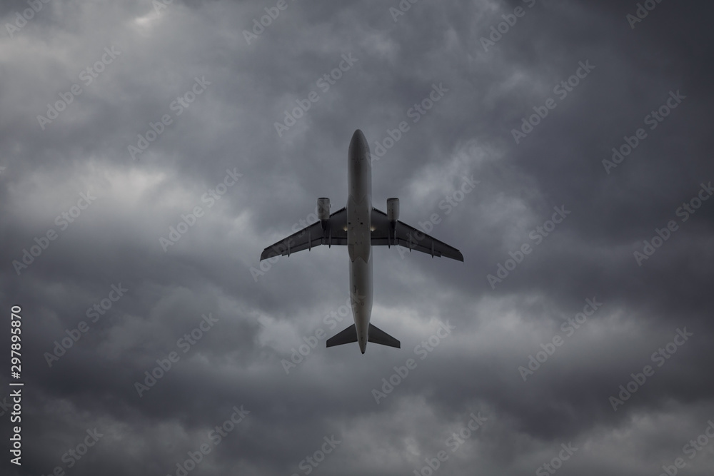 Fototapeta premium A passenger plane in the cloudy sky. Commercial plane taking off on background of storm clouds, turbulence concept.
