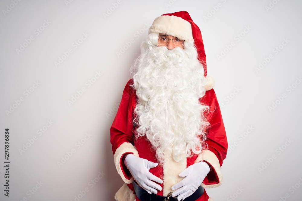 Middle age handsome man wearing Santa costume standing over isolated white background Relaxed with serious expression on face. Simple and natural looking at the camera.