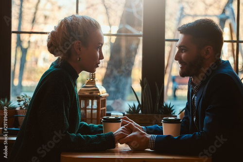 Handsome man and beautiful woman spend their time together while drinking coffee at cafeteria.