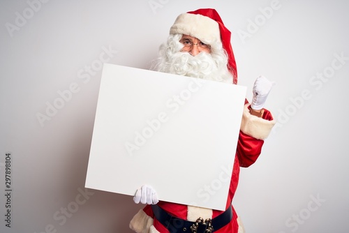 Middle age man wearing Santa Claus costume holding banner over isolated white background pointing and showing with thumb up to the side with happy face smiling © Krakenimages.com