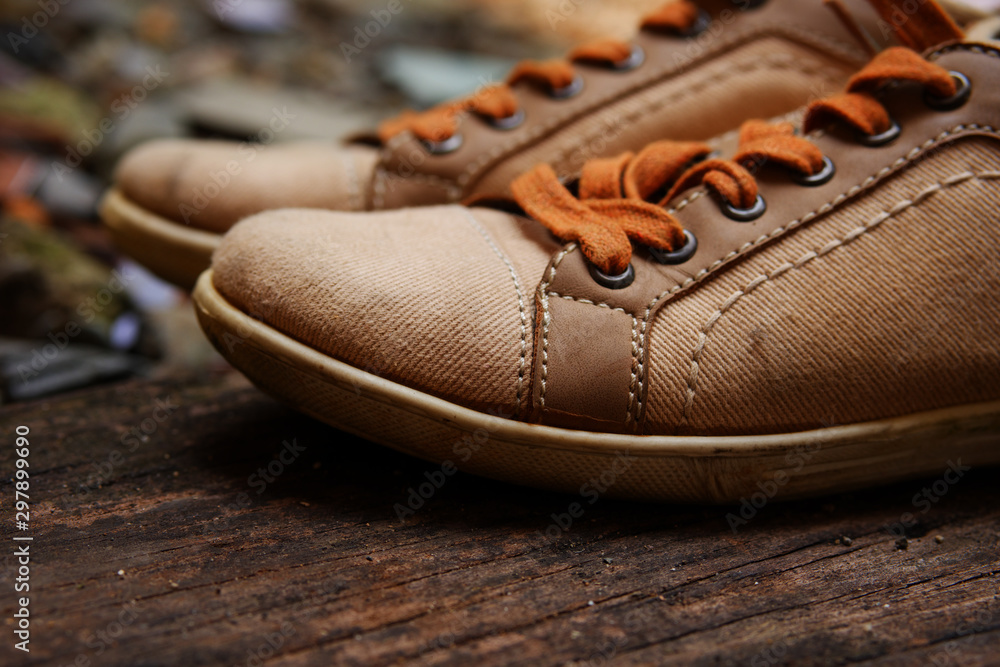 Stylish pastel sneakers with orange shoelaces on rustic old wooden boards with dark textures. Sport shoes concept. Stylish pastel sneakers with orange shoelaces on rustic old wooden boards with dark textures. Sport shoes concept.