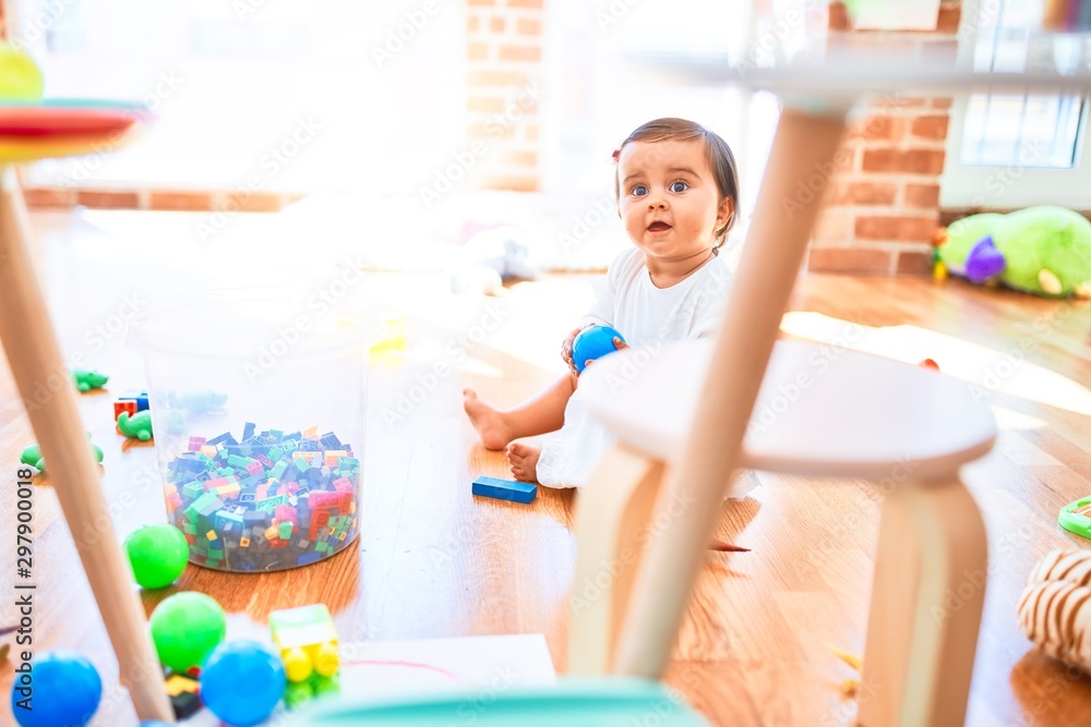 Beautiful infant happy at kindergarten around colorful toys Beautiful infant happy at kindergarten around colorful toys