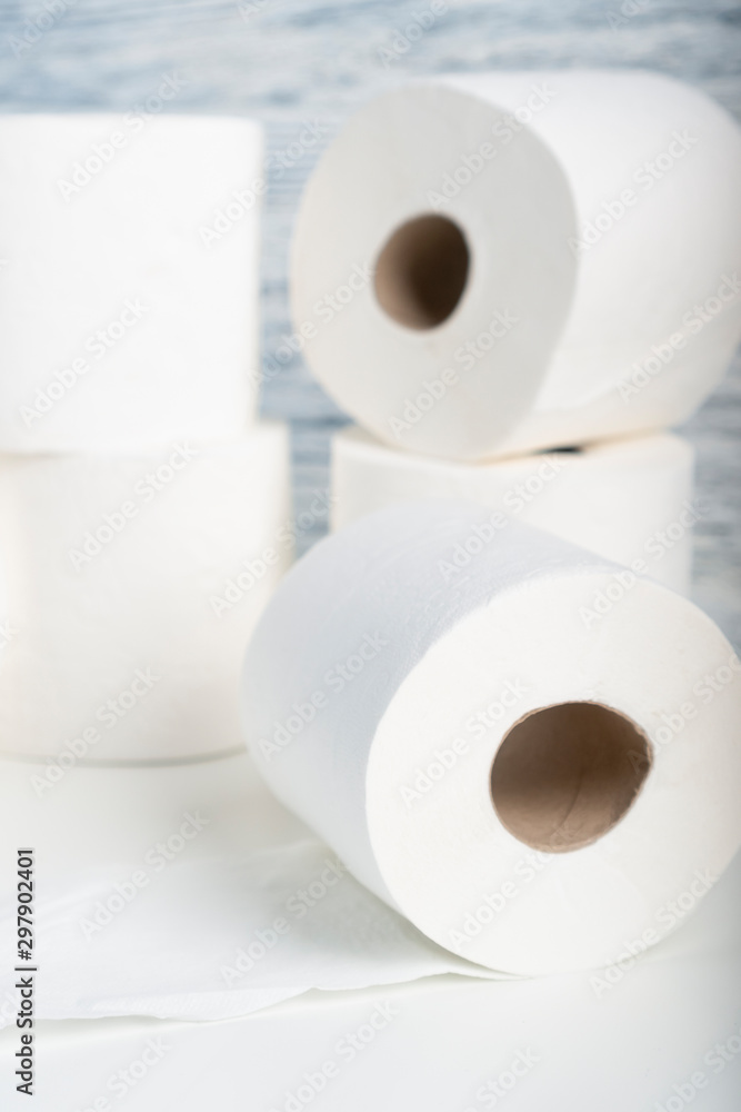 A pile of toilet paper rolls on a white table on a background of blue wall texture. The concept of using natural materials for hygiene products A pile of toilet paper rolls on a white table on a background of blue wall texture. The concept of using natural materials for hygiene products