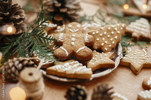 Tableau sur toile Christmas gingerbread cookies on vintage plate and anise, cinnamon, pine cones, cedar branches  with golden lights on rustic table