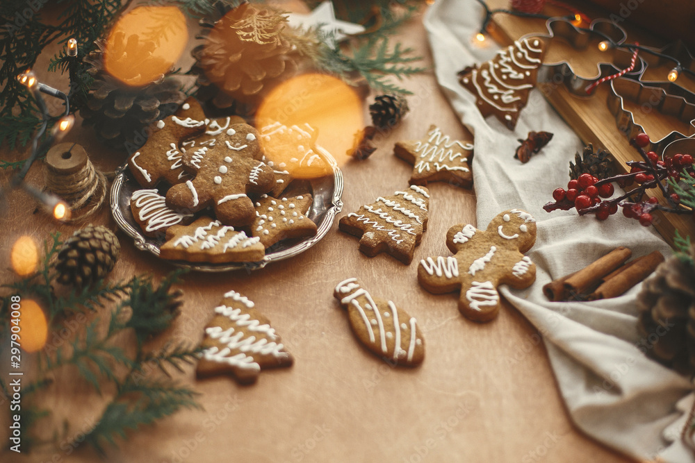 Merry Christmas. Festive gingerbread cookies with anise, cinnamon, pine cones, cedar branches and golden lights bokeh on rustic table. Atmospheric image. Seasons greetings Merry Christmas. Festive gingerbread cookies with anise, cinnamon, pine cones, cedar branches and golden lights bokeh on rustic table. Atmospheric image. Seasons greetings