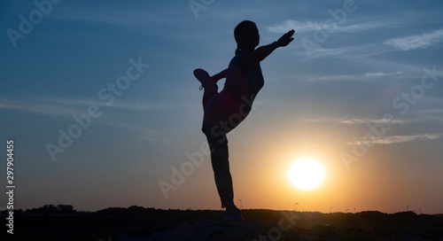 Young woman is practicing yoga in natarajasana pose at mountain lake