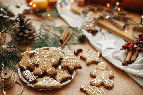 Papier peint Christmas gingerbread cookies on vintage plate and anise, cinnamon, pine cones, cedar branches  with golden lights on rustic table