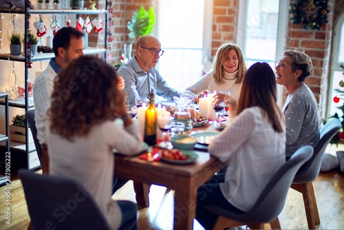 Family and friends dining at home celebrating christmas eve with traditional food and decoration, all sitting on the table together © Krakenimages.com