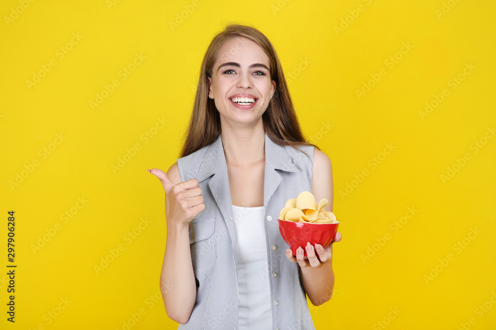 Young beautiful girl with potato chips in bowl on yellow background Young beautiful girl with potato chips in bowl on yellow background