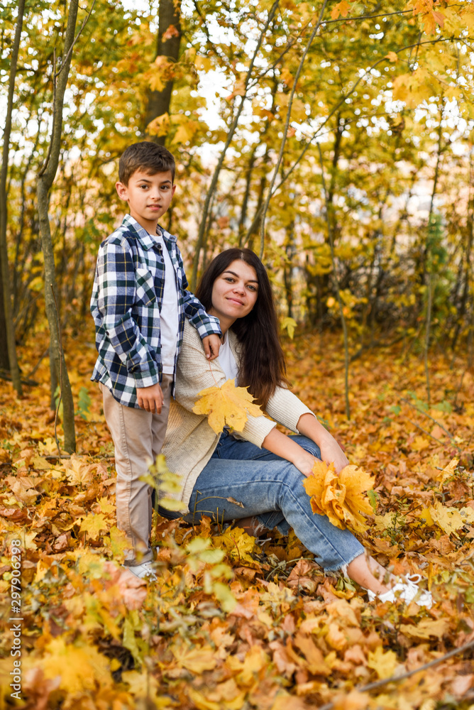 Fototapeta premium mom and son collecting leaves in autumn park. copy space
