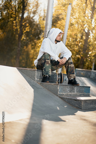 Man in skatepark with skateboard on warm autumn day