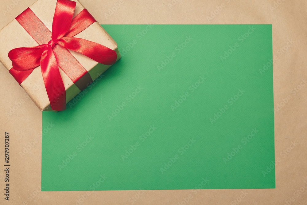 Christmas greeting card. Green mockup board with a gift box on a brown background. Copy space. Christmas greeting card. Green mockup board with a gift box on a brown background. Copy space.
