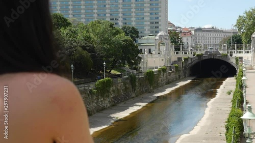 Brunette looks at drought vienna river and Caroline Bridge in Stadtpark, back view photo