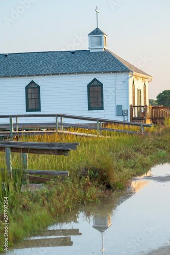 Chapel cross reflected in water left behind by high tide in a marsh creek