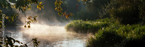 Early morning on the Nepryadva River in the Tula Region. Fog above the water in the sun. Tree branches over water in a fog. Russia, the village of Monastyrshchina. photo