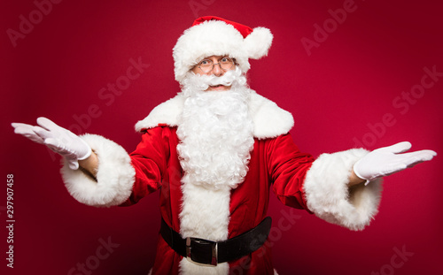 What a surprise! Authentic Santa Claus is posing spreading his hands for a hug or to express his astonishment.