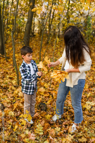 mom and son collecting leaves in autumn park. copy space