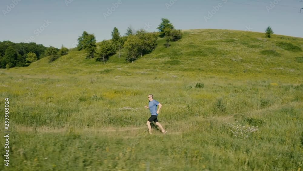 Man runner run outdoor in the field. Airial video from drone. Man runner run outdoor in the field. Airial video from drone.