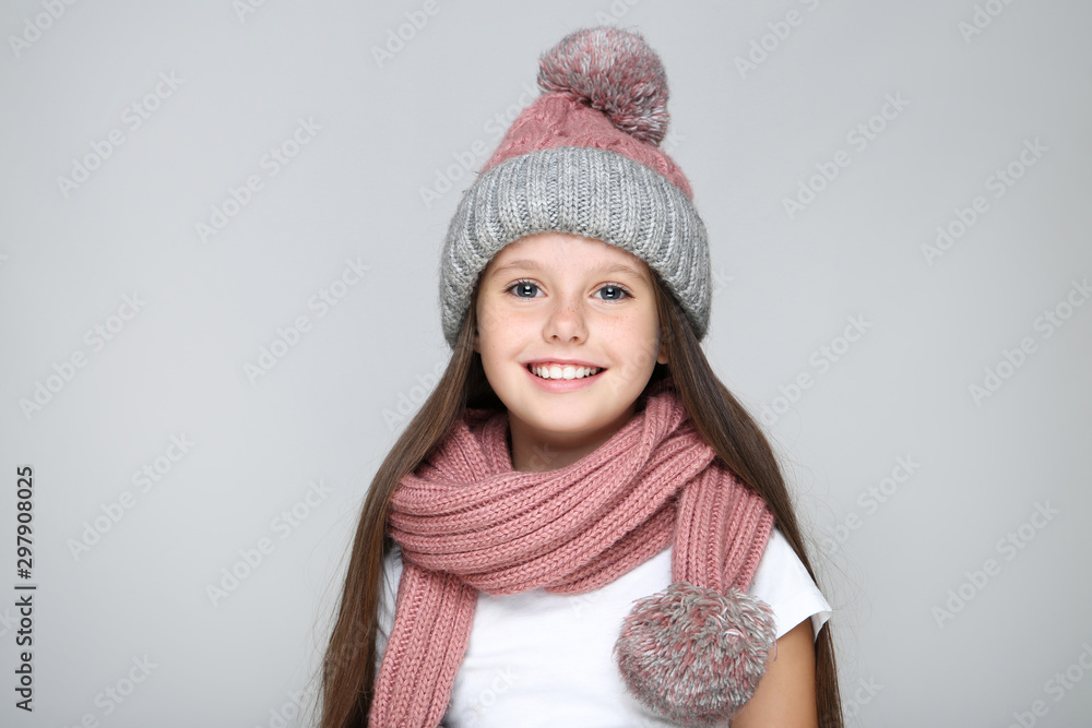 Little girl in hat and scarf on grey background Little girl in hat and scarf on grey background
