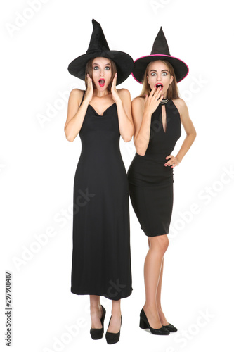 Two young surprised women in black halloween costumes on white background