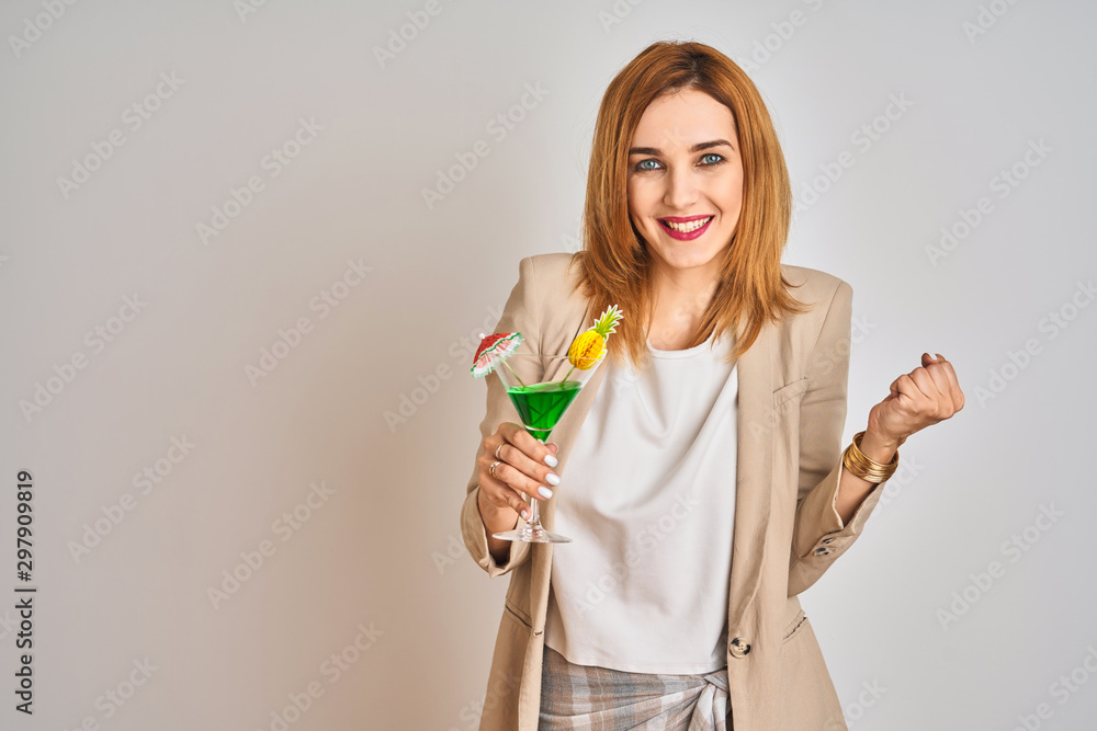 Redhead caucasian business woman drinking a summer cocktail over isolated background screaming proud and celebrating victory and success very excited, cheering emotion Redhead caucasian business woman drinking a summer cocktail over isolated background screaming proud and celebrating victory and success very excited, cheering emotion