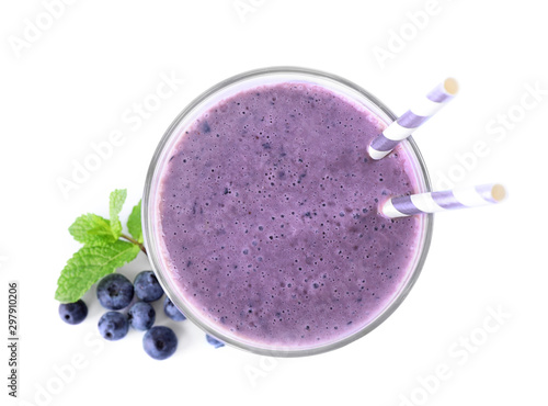 Tasty fresh milk shake in glass and blueberries on white background, top view